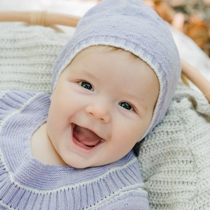Süßes lachendes Baby im Korb beim Outdoorshooting
