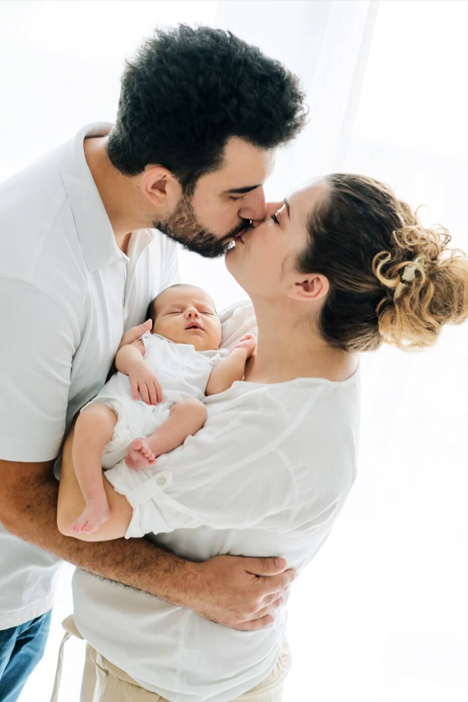 Newborn-Shooting Kuessende Eltern mit Baby im Arm