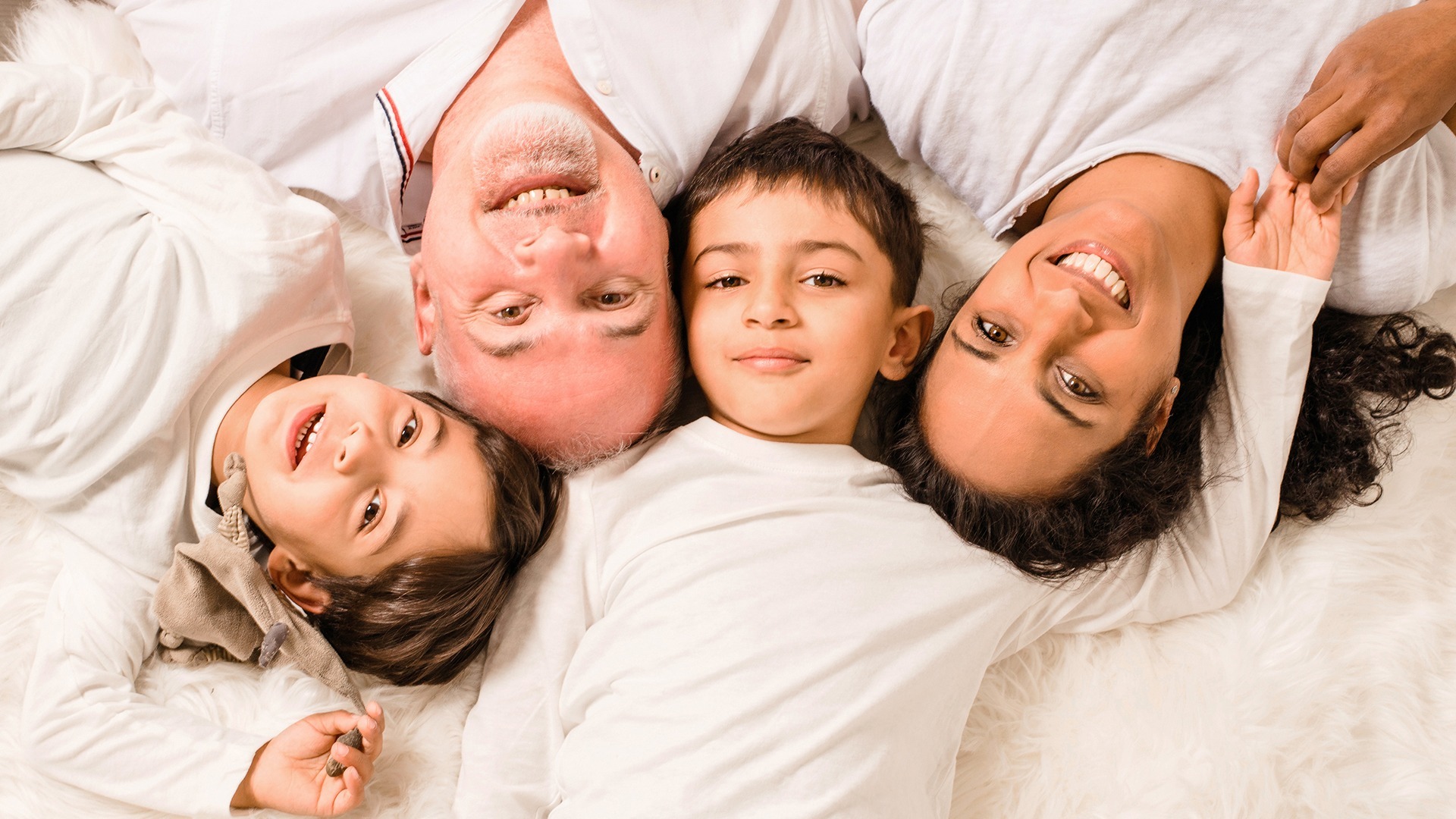 Family of four lying with their heads together on a light blanket