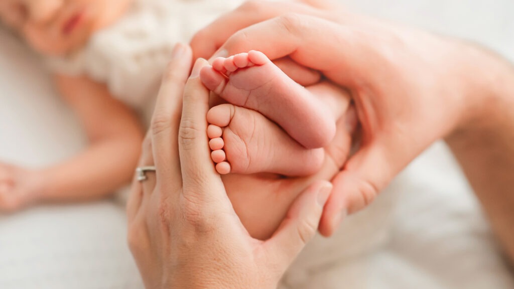 Mutter äolt Babyfüße bei dem Neugeborenen Shooting