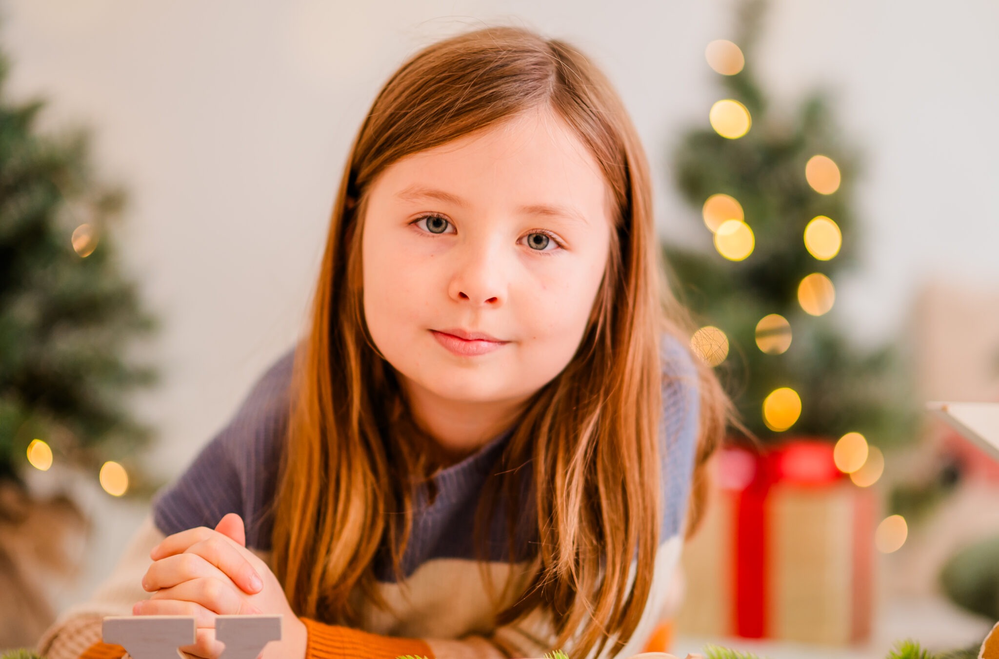 Child in front of Christmas trees with lights and presents